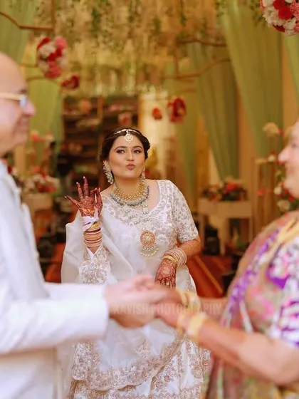 A playful, candid shot of the bride making a fun gesture towards her parents, showing the lighthearted side of family love.