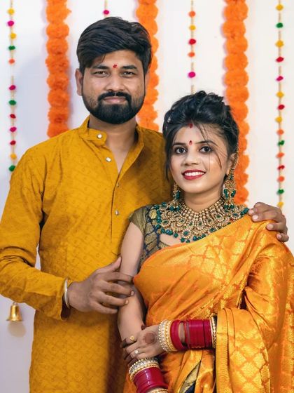 A happy couple's portrait from their Diwali celebration, dressed in traditional yellow outfits.