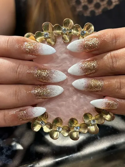 A glamorous white and gold glitter ombre on sharp stiletto nails, perfect for a bridal or party look.
