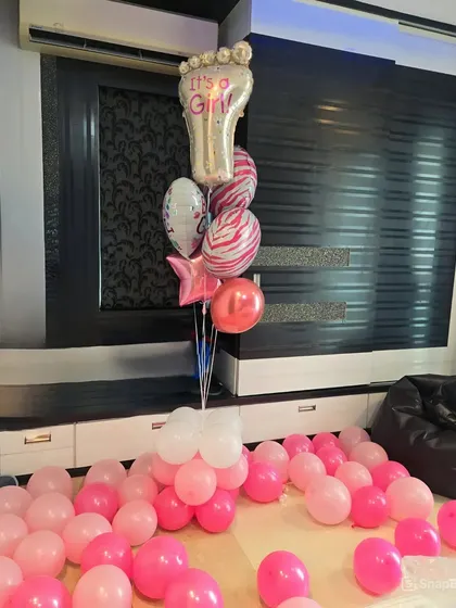 A simple yet sweet "It's a Girl" balloon arrangement for a home welcome. The floor is covered in pink and white balloons, anchored by a beautiful bouquet featuring a large 'It's a Girl' foot-shaped foil balloon.