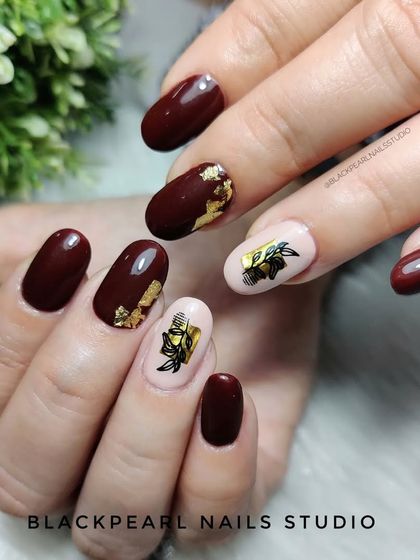 An elegant design of brown nails with golden foil and chic sticker art on a nude base.