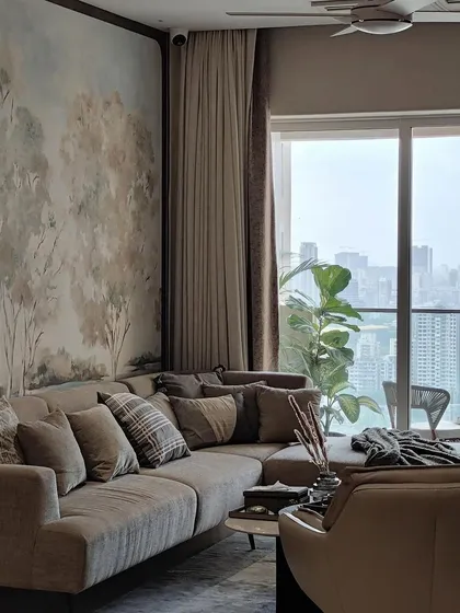 This living space, designed by Arkamine Design, features our framed artisanal wallpaper to unite the room with natural beauty. The soft, painterly treescape creates a harmonious backdrop for the custom sectional sofa, blending the interior with the cityscape beyond.