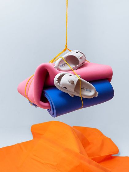 A playful, conceptual shot featuring kids' shark-themed clogs suspended with yoga mats. The bright colors and unusual composition grab attention instantly.
