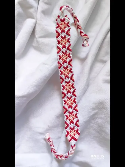 The full length of the red and pink geometric bracelet, ready to be tied on.