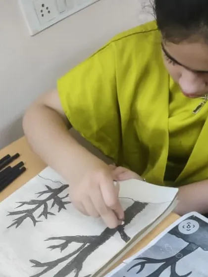 A student works on a charcoal drawing of a tree, learning about texture and shading to create a more realistic effect.