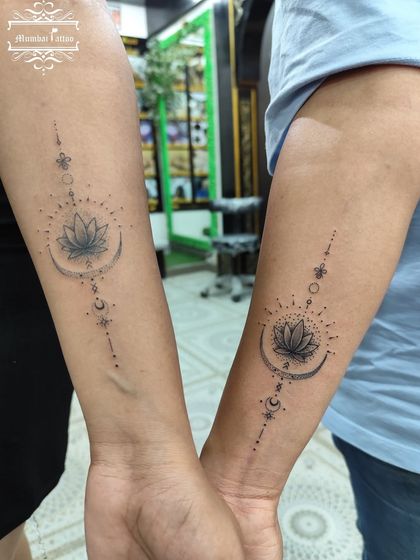A matching couple tattoo featuring a lotus on a crescent moon with celestial details. This Unalome-inspired design symbolizes the path to enlightenment and shared spiritual growth.