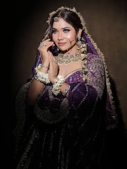 A full portrait of a bride in a purple lehenga, complete with floral hand jewellery. This showcases a complete, styled look from head to toe.
