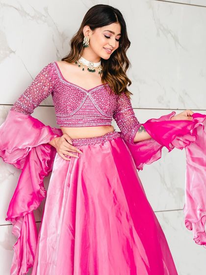 A close-up of the rose pink lehenga, highlighting the detailed blouse and the playful, flowing ruffled sleeves. It's a perfect blend of glamour and fun.