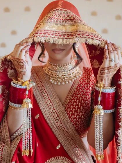 A timeless bridal portrait. Draped in a classic red Sabyasachi veil, this frame captures the quiet grace, anticipation, and elegance of a bride in the moments before her ceremony.