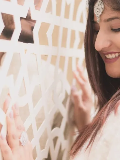 A creative and romantic shot of a couple on their engagement day. The use of a traditional jali screen adds an artistic element, creating a sense of a secret, shared moment.