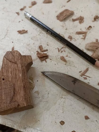 The whittled dog next to the knife used to carve it. Whittling is a relaxing and portable form of woodworking that you can do almost anywhere.