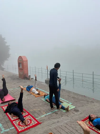 A class practicing leg raises by the river, a great exercise for core strength, in the fresh morning air.