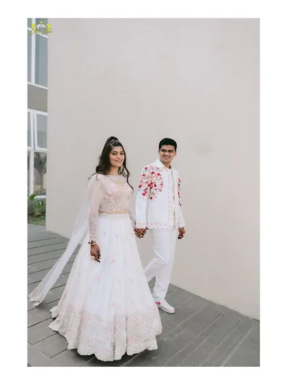 A simple and sweet portrait of Kartik and Sakshi walking hand-in-hand, showcasing their coordinated white outfits.