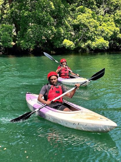 Two participants practice their kayaking skills together on the vibrant green waters of the Kali river.
