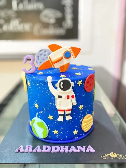 A space exploration cake for Araddhana's 3rd birthday. This deep blue cake features an astronaut, rocket, and planets.