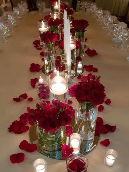 A classic romantic dinner table setup. I used tall glass vases with red roses, floating candles, and scattered petals on a mirrored base to create this timeless and elegant look.
