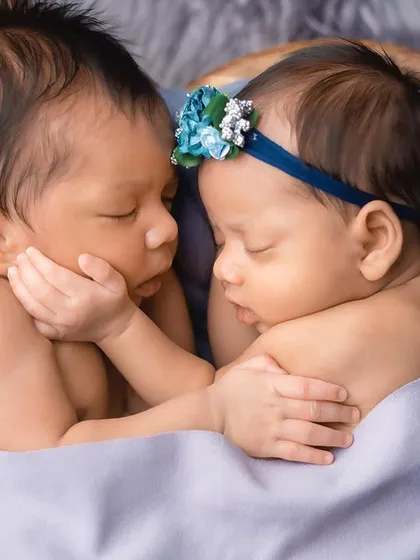 A close-up of the newborn twins, their faces close together as they sleep. This shot highlights their delicate features and the peacefulness of their bond.