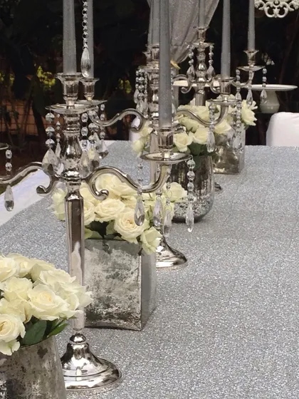 An elegant and glamorous baby shower tablescape. The silver sequin runner, crystal candelabras, and white roses created a sparkling and sophisticated look.