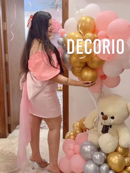 A close-up of the birthday girl with a teddy bear and balloon arrangement from her 'Bow-tiful' themed party.