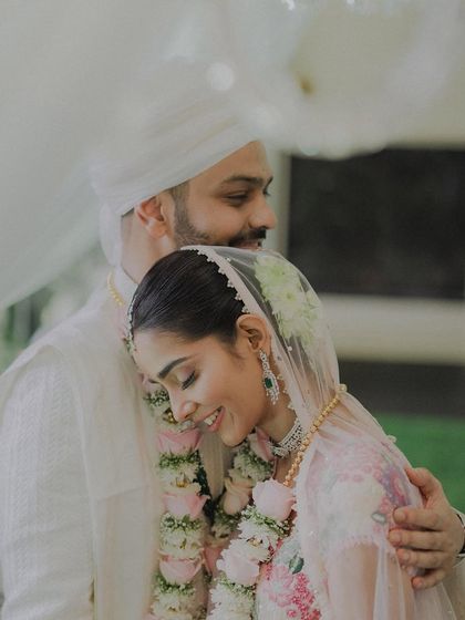 A tender embrace, a moment of quiet comfort on a busy wedding day. The bride rests her head on the groom's shoulder, a simple gesture that speaks volumes about their love.