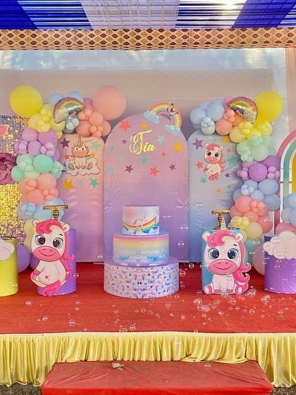 The full stage for the unicorn party, showcasing the cake on a themed pedestal and the colorful, whimsical decorations.