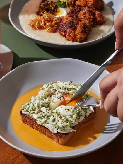 Our Warm Herb Garlic Butter Lump Crab Toast. A generous amount of fresh crab meat sits atop a toasted slice of bread, surrounded by a rich prawn bisque.