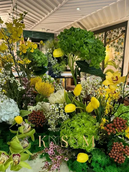 This grazing table arrangement is a lush collection of exotic flowers in vibrant yellows and greens. The design is meant to feel wild and untamed, reflecting the biodiversity of a tropical rainforest.