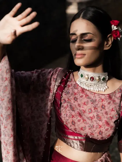 An artistic shot capturing the play of light and shadow on our muse, dressed in the elegant Brick Maroon lehenga set.
