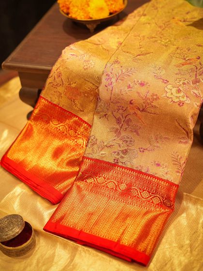 A stunning gold Kanjivaram with multi-color floral meena jal zari weaving and a vibrant red border, perfect for weddings.