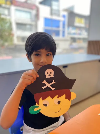 Look at that proud smile. Our workshops blend performance with hands-on activities, like creating this pirate craft, allowing children to bring their imaginative characters to life and take home a piece of their creative work.