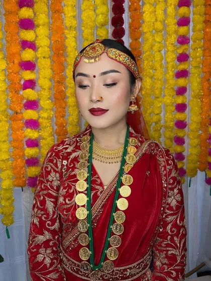 A serene portrait of a flawless Nepali bride. Her makeup is kept classic and clean with a red lip and subtle eye makeup to let her traditional attire and unique coin necklace shine.