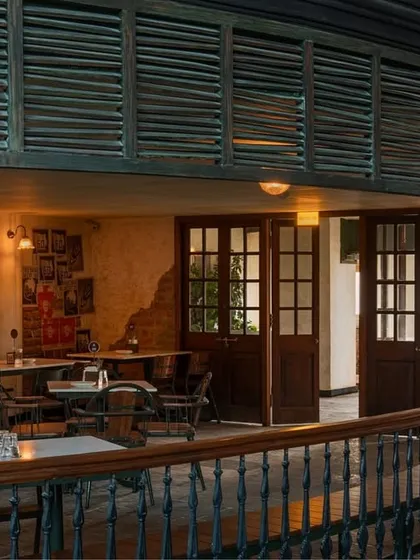 A cozy nook under the mezzanine, featuring vintage-style doors and a gallery wall of prints. This area was designed to feel like a private corner within the larger establishment.