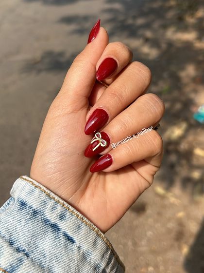 A classic and elegant set featuring a deep red polish on almond-shaped nails. I added a single gold bow charm as a delicate and luxurious accent.