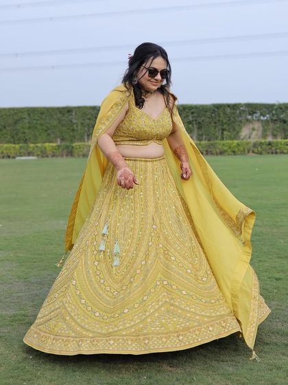 A full view of the bride's vibrant mehendi outfit. The flowy lehenga with its unique color and detailed embroidery was perfect for a fun, outdoor daytime event.