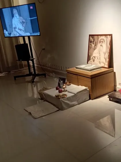 The altar during a Sanidhi Pooja, with a live satsang on screen. This blending of the physical and digital allows us to connect with the Guru's presence wherever we are.