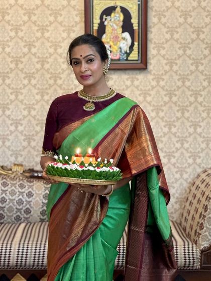 Holding a tray of lamps, our client looks serene and graceful in her traditional Kanchipuram silk saree.