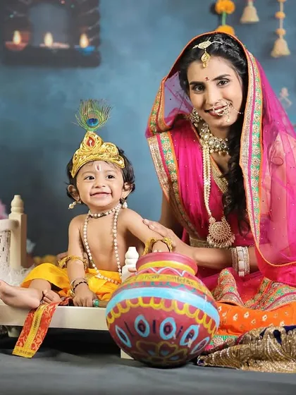 Yashoda and baby Krishna smiling for the camera, a perfect portrait showcasing their love and the vibrant, detailed setup.