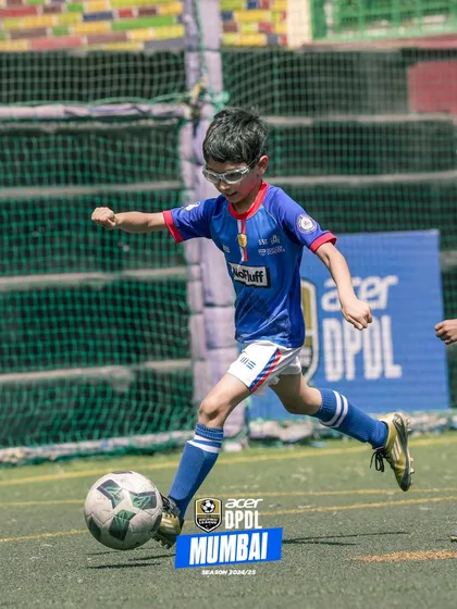 A young player with protective glasses, fully focused on striking the ball.