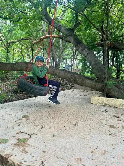 A happy camper enjoying a classic tire swing. Simple outdoor play is at the heart of our philosophy, letting kids just be kids.