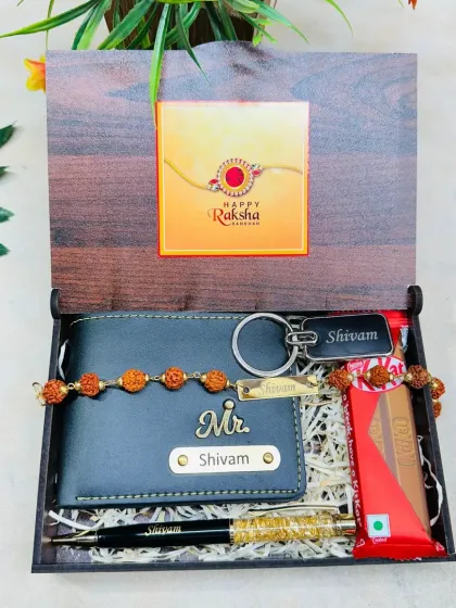 A classic Rakhi gift set in a wooden box. It includes a personalized wallet and pen, a rakhi with a matching bracelet, and a chocolate bar.