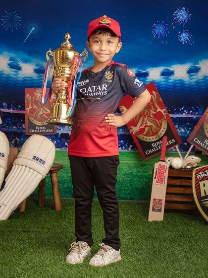 Ee sala cup namde! This young fan proudly holds the trophy, showing his unwavering support for RCB.