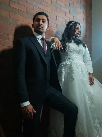 A cool, editorial-style wedding portrait in black and white. The strong poses and dramatic shadows create a high-fashion, modern look.