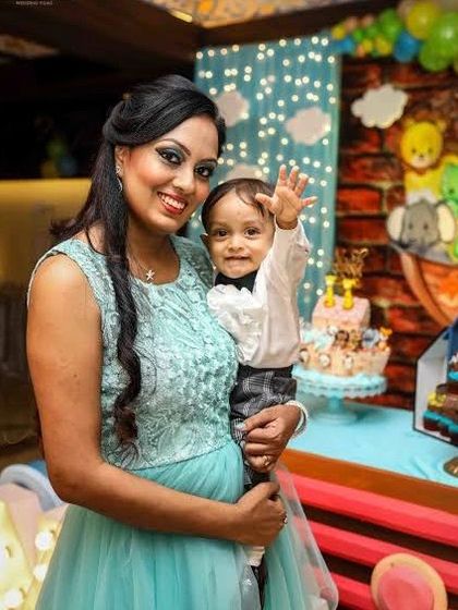 A mother holds her son, who is waving happily at the camera. This is a perfect example of the joyful and interactive portraits we create.