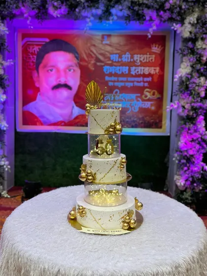 The 50th birthday cake set up at the party venue, right in front of a personalized banner for the birthday person.