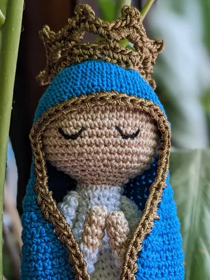 A close-up on the face of the Mother Mary doll, showing her closed eyes in prayer.