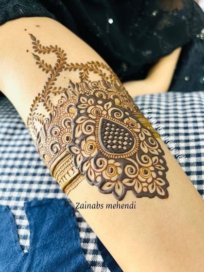 A close-up of the paisley motif on Ameena's arm, with intricate checkerboard filling.
