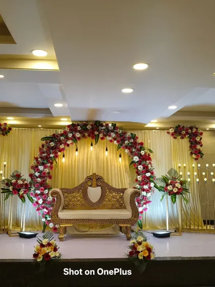A wide-angle shot of the reception stage, showing the full impact of the floral arch and the symmetrical arrangement of lights and flower stands.