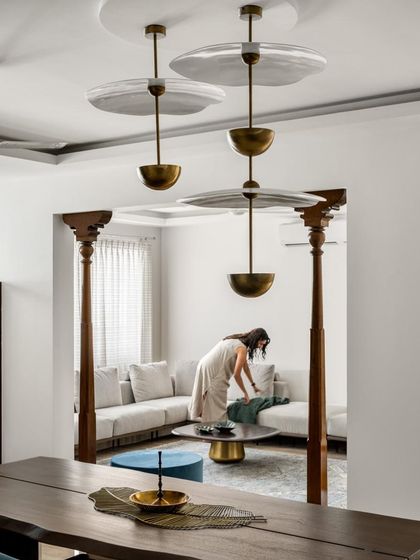 A person arranging cushions in a living space defined by traditional wooden pillars. This image shows how these historical elements are integrated into a modern, functional home.