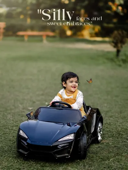 Silly faces and sweet embraces. A happy boy smiles as a butterfly lands near his toy car.