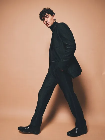 This full length shot showcases a monochromatic suit against a neutral backdrop, emphasizing the clean lines and impeccable fit that are the hallmarks of true sartorial style.